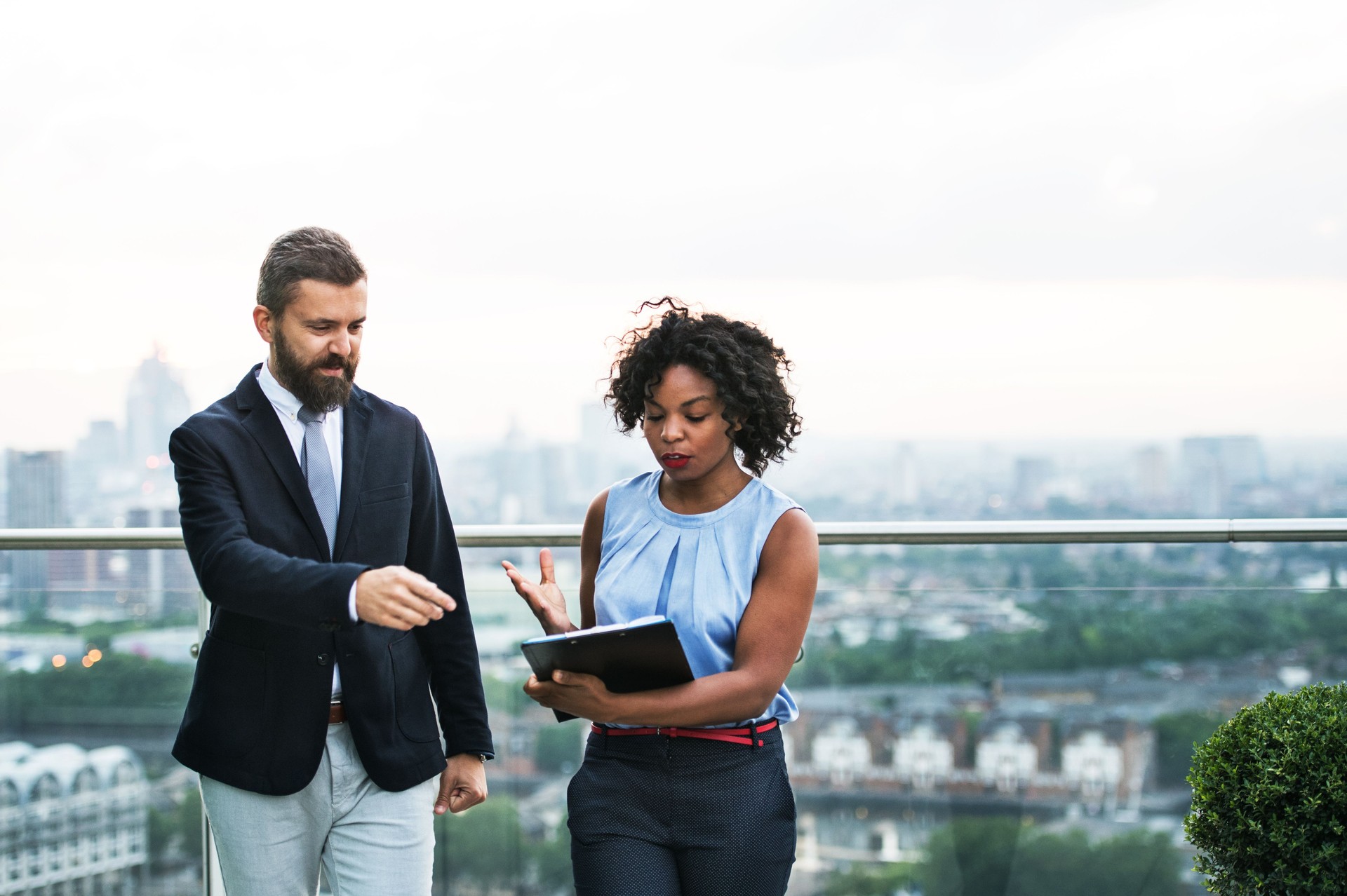 A portrait of two businesspeople standing against London view panorama.